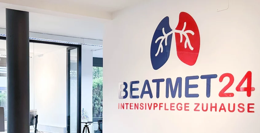 Empfangsbereich von beatmet24 mit dem Unternehmenslogo „beatmet24 Intensivpflege Zuhause“ an der Wand.