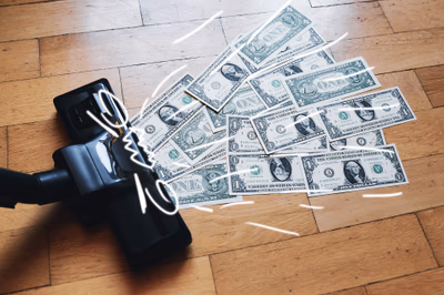 Staubsauger saugt Dollarnoten auf – als visuelle Metapher für steigende KI-Nutzungskosten durch tokenbasierte Abrechnung und große Kontextverarbeitung.