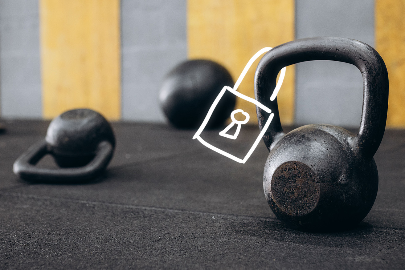 Black kettlebells on a gym floor, with a large kettlebell in the foreground.