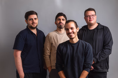 Gruppenfoto der vier IOWIS-Co-Founder Bozidar Zivanovic, Luca Perozzi, Davide Perozzi und Peter Müller vor neutralem Hintergrund.